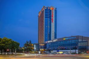 a tall building with a sign on the side of it at Songjiang New Century Grand Hotel Shanghai in Songjiang