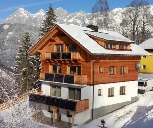 a house in the snow with mountains in the background at Chalet Leni in Schladming