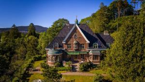 une grande maison sur une colline avec des arbres dans l'établissement Unique Victorian Villa with private coastline, à Bergen
