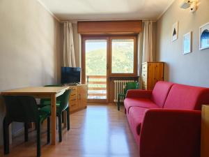 uma sala de estar com um sofá vermelho e uma mesa em Hostdomus - Color Apartment em Sestriere