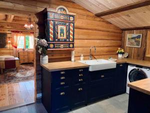 a kitchen with blue cabinets and a sink in a cabin at Sjarmerende tømmerhytte på gårdstun in Baukål