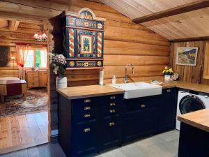 a kitchen with blue cabinets and a sink in a cabin at Sjarmerende tømmerhytte på gårdstun 
