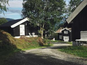 a black building with a bench and a house at Sjarmerende tømmerhytte på gårdstun in Baukål