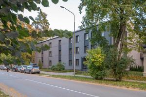 un bâtiment sur le côté d'une rue avec des voitures garées dans l'établissement Dzintaru Beachside 1BR Apartment With Courtyard View, Walk to Nature & Sea, à Jurmala