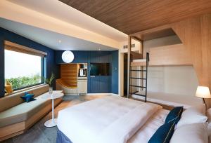 a bedroom with a large white bed and a kitchen at The Suites Hotel Jeju in Seogwipo