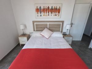 sypialnia z czerwono-białym łóżkiem z 2 lampami w obiekcie Tinérfe el grande 12 w Adeje