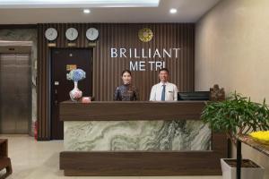 two men standing at a counter in a lobby at Brilliant Me Tri Hotel & Spa in Hanoi
