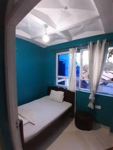Cette chambre bleue comprend un lit et une fenêtre. dans l'établissement Sasha Holiday Apartments #B5, à Mtwapa