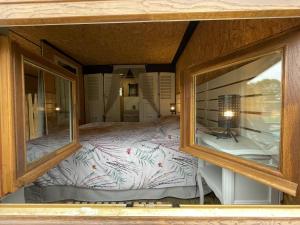 a bedroom with a large bed through two windows at Le Cabanon in Dangeau