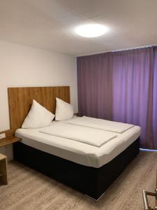 Bett in einem Zimmer mit einem lila Vorhang in der Unterkunft Hotel am Bahnhof in Feldkirch
