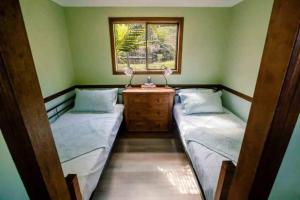 two beds in a room with a window at Birdsong Train Carriage Cabin with Outdoor Bath in Palmwoods
