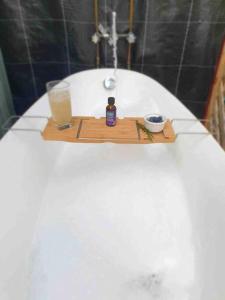 a bath tub with a tray with a bottle of soap and a glass at Birdsong Train Carriage Cabin with Outdoor Bath in Palmwoods