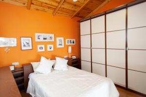 ein Schlafzimmer mit einem weißen Bett und einer orangefarbenen Wand in der Unterkunft Jaen Catedral histórico in Jaén