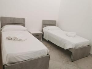 2 letti in una camera con lenzuola bianche di Residence Fortunato a Policastro Bussentino