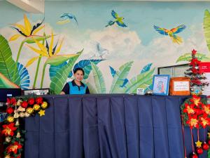 um homem parado atrás de uma mesa em frente a uma parede com pássaros em Gplace Hotel em Cebu
