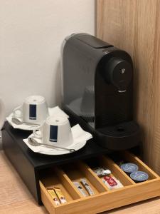 a television sitting on a shelf with cups and saucers at Avento Hotel Hannover in Hannover