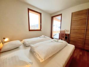 two beds in a room with two windows at AlmApp Nassfeld in Sonnenalpe Nassfeld