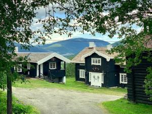 dois edifícios negros com montanhas ao fundo em Eventyrlig Tømmerhytte på Gårdstun em Vinstra