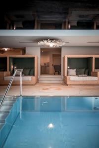 a large swimming pool in a room with a couch at Hotel Alpenhof in Rasùn di Sotto