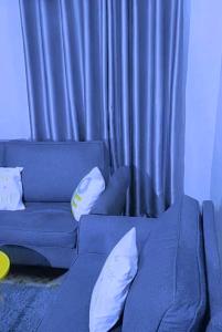 a blue couch with white pillows in front of a curtain at Tulivu Homes in Embu