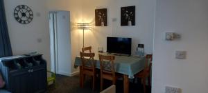 a room with a table with chairs and a television at The Old Post Office Apartment in Adlington