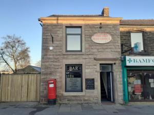 an old brick building with a red mailbox in front of it at The Old Post Office Apartment in Adlington