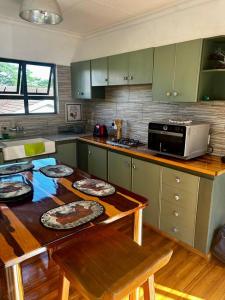 eine Küche mit grünen Schränken und einem Tisch mit Tellern darauf in der Unterkunft Cosy one bedroom garden cottage in Tugela Mouth