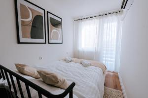 a white bedroom with a bed and a window at Apartman Vista in Daruvar