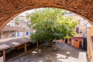 einen Torbogen über einen Innenhof mit einem Baum und Gebäuden in der Unterkunft Central Hôtel in Cerbère