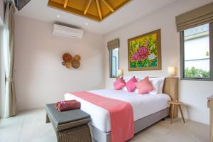 een slaapkamer met een groot wit bed met roze kussens bij Dalaa 8 in Kamala Beach