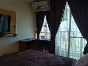 a bedroom with a bed and a desk and windows at Pleasant05tifolia in Jakarta