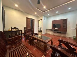 un soggiorno con mobili in legno e TV a schermo piatto di LA SEREN VILLA a Pondicherry