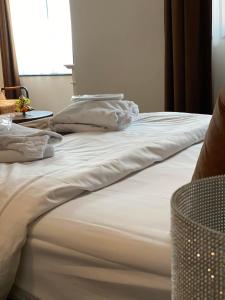 Una cama con sábanas blancas y almohadas. en Hotel De Boskar Peer en Peer