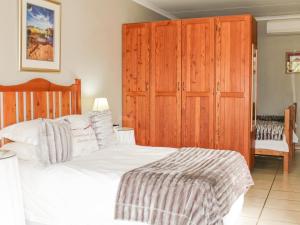 a bedroom with a white bed and wooden cabinets at Blommenberg Guest House in Clanwilliam