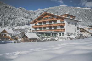 ein großes Gebäude im Schnee vor einem Berg in der Unterkunft Hotel Alpenhof in Rasùn di Sotto