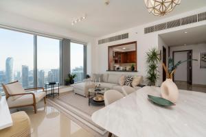 una sala de estar con muebles blancos y ventanas grandes. en Prestige Living 2BR with Full Burj Khalifa and Fountain View by Auberge, en Dubái