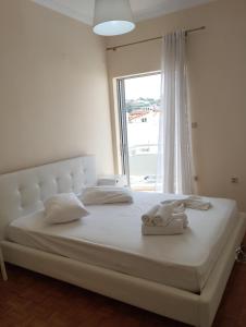 Schlafzimmer mit einem großen weißen Bett und einem Fenster in der Unterkunft Ionias Penthouse in Korinthos