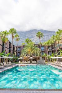 a large swimming pool with palm trees and chairs at Golden Sun Hotel Adult Only in Beldibi