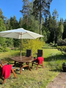 a picnic table and chairs with an umbrella at Metsäkoto, laadukas huoneisto Eurassa. in Rauma
