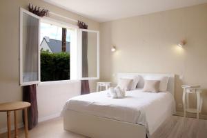 ein Schlafzimmer mit einem weißen Bett und einem Fenster in der Unterkunft Villa des Daules in Cancale