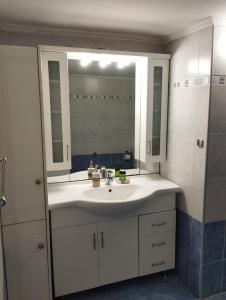 ein Badezimmer mit einem weißen Waschbecken und einem Spiegel in der Unterkunft Ionias Penthouse in Korinthos