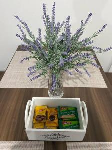 un vase avec des fleurs violettes et des collations sur une table dans l'établissement Casa Uni residencial 03, à Coronel Vivida