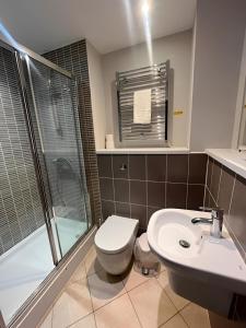 a bathroom with a toilet and a sink and a shower at Quayside Apartments in Cardiff