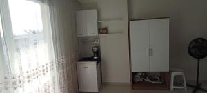 uma cozinha com um armário branco e uma janela em Sabinanın sıcak evi em Didim
