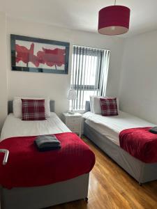 Riverview Apartments في غلاسكو: غرفة نوم بسريرين وبطانية حمراء