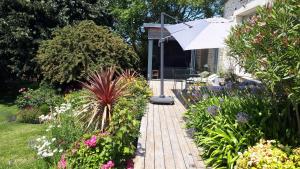 un jardín con una pasarela de madera con sombrilla en Le Vieux Couvent & SPA, en Sibiril