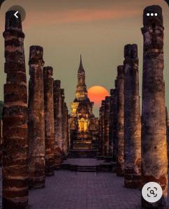 a sunset over a temple with columns and a tower at Toon guesthouse in Sukhothai