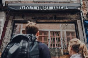 un hombre y una mujer mirando por la ventana de una tienda en Les 3 Cabanes Urbaines - centre historique, en Namur