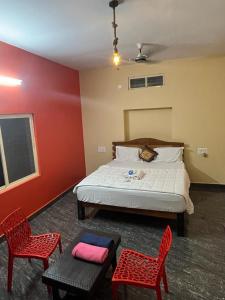 ein Schlafzimmer mit einem Bett und zwei roten Stühlen in der Unterkunft Goud's Home stay in New Hampi
