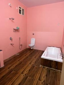 ein rosafarbenes Badezimmer mit einem WC und einer Badewanne in der Unterkunft Goud's Home stay in New Hampi
